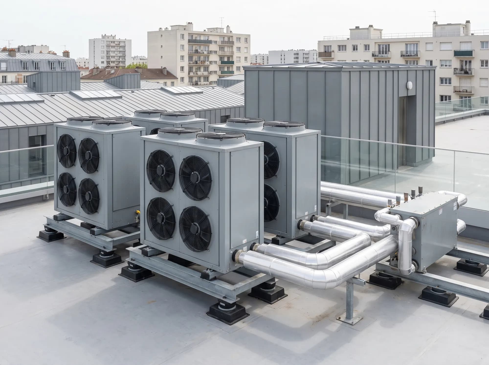 Quatre pompes à chaleur air/eau sur châssis antivibratiles, reliées à un module hydraulique sur le toit d'un immeuble de bureaux en ville