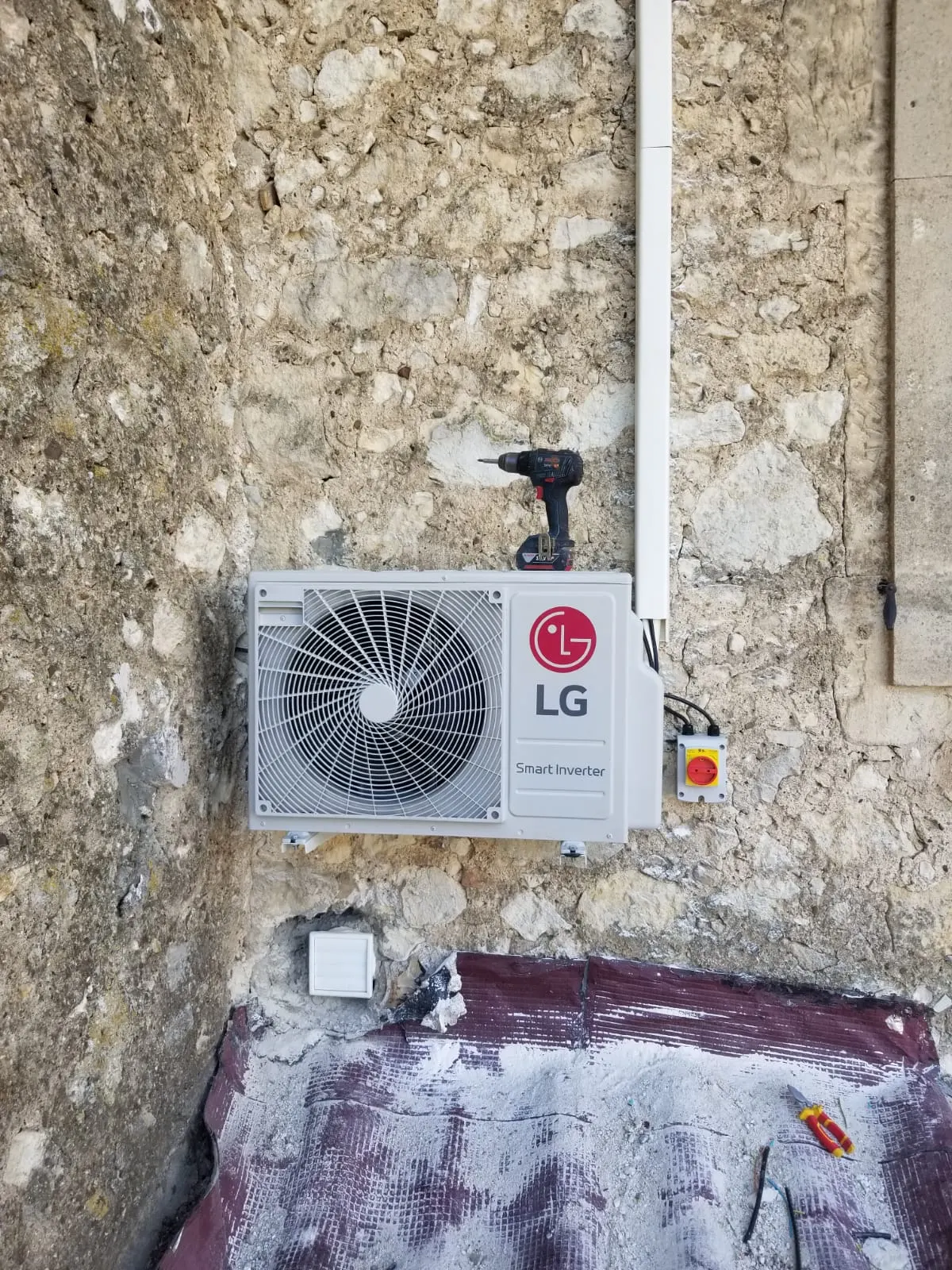 Unité extérieure LG posée en façade sur mur en pierre