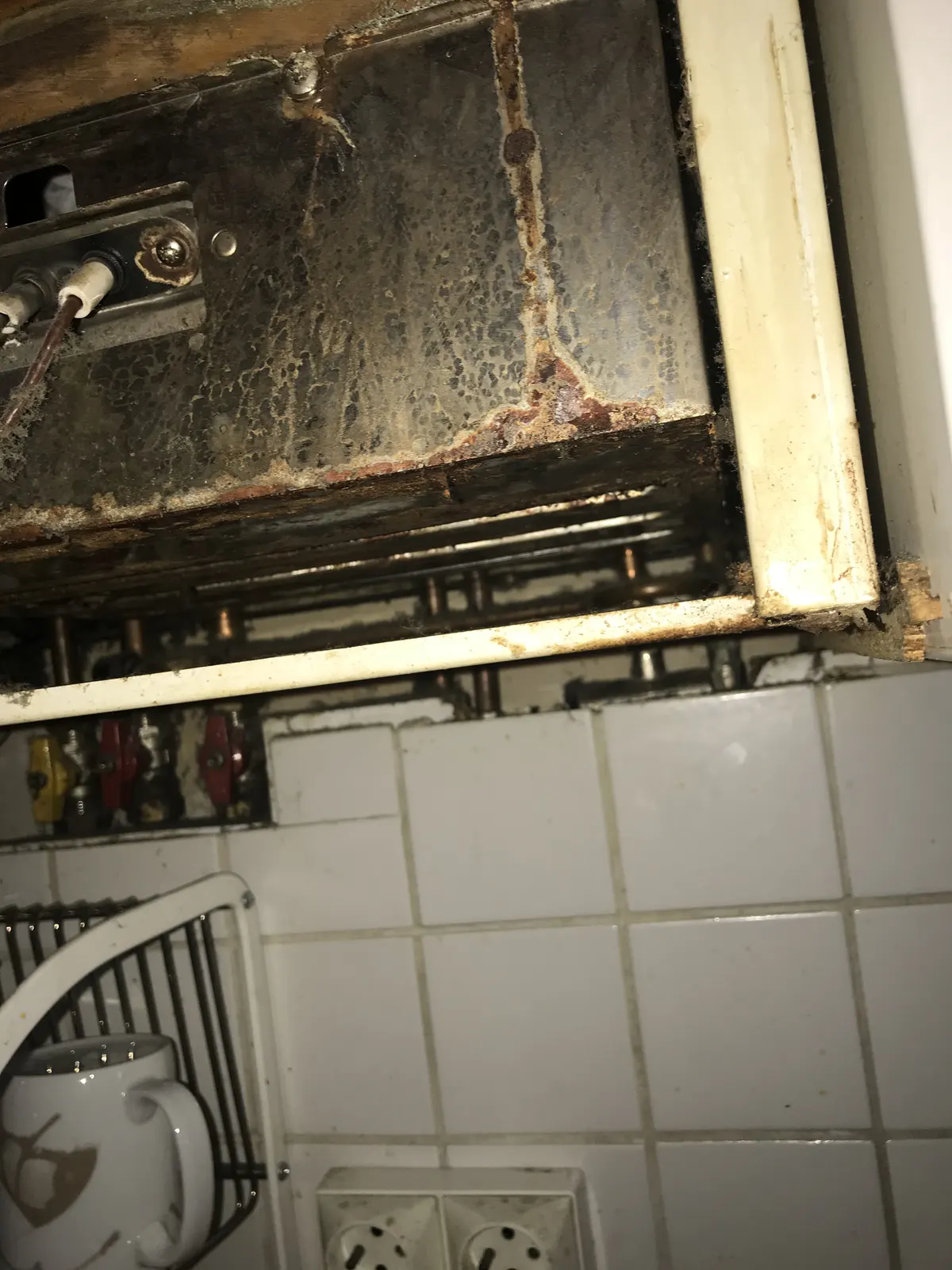 Dessous encrassé d'un ancien chauffe-bain gaz avant dépose