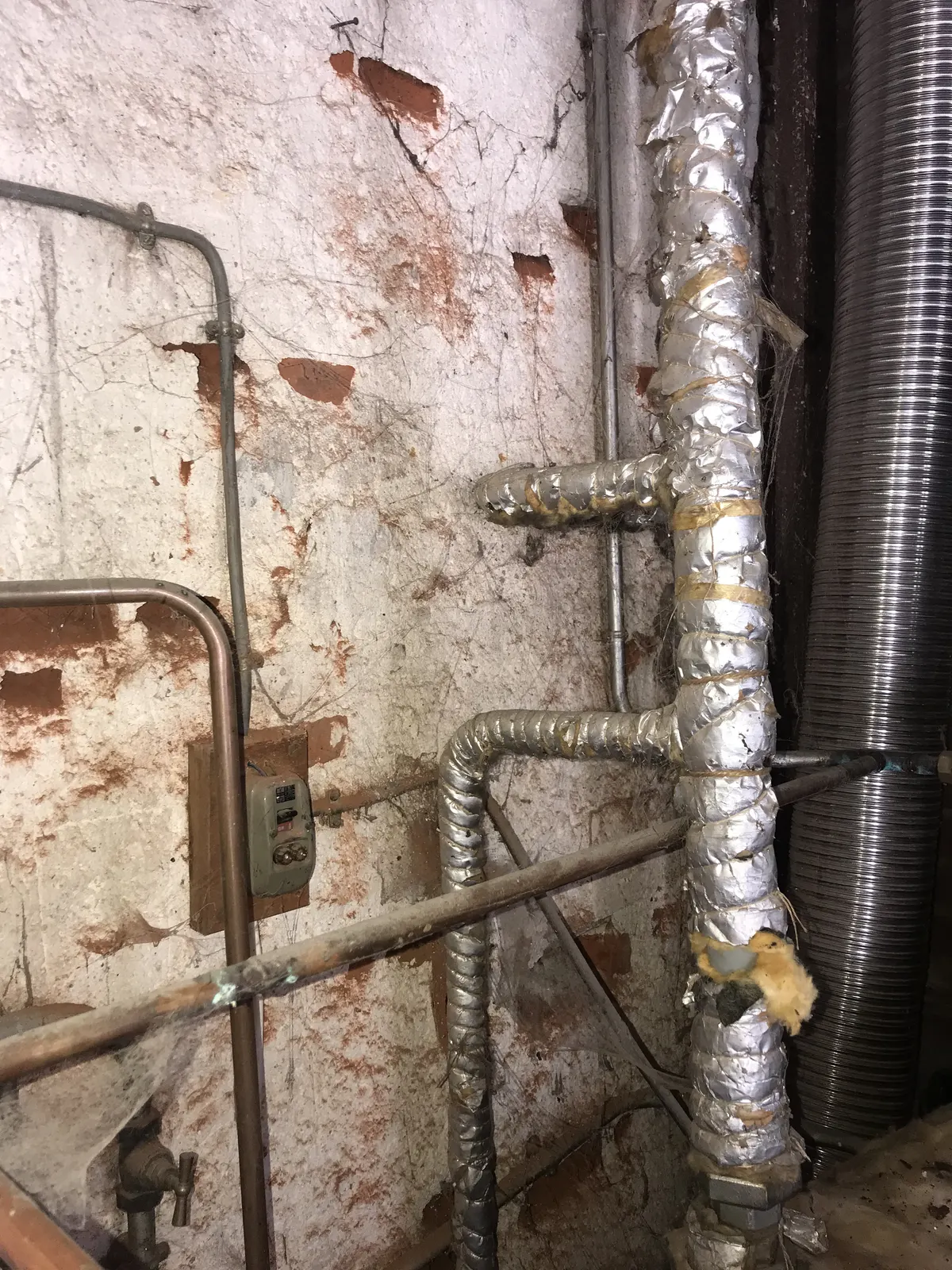 Réseaux de tuyauteries calorifugées le long d'un mur de chaufferie